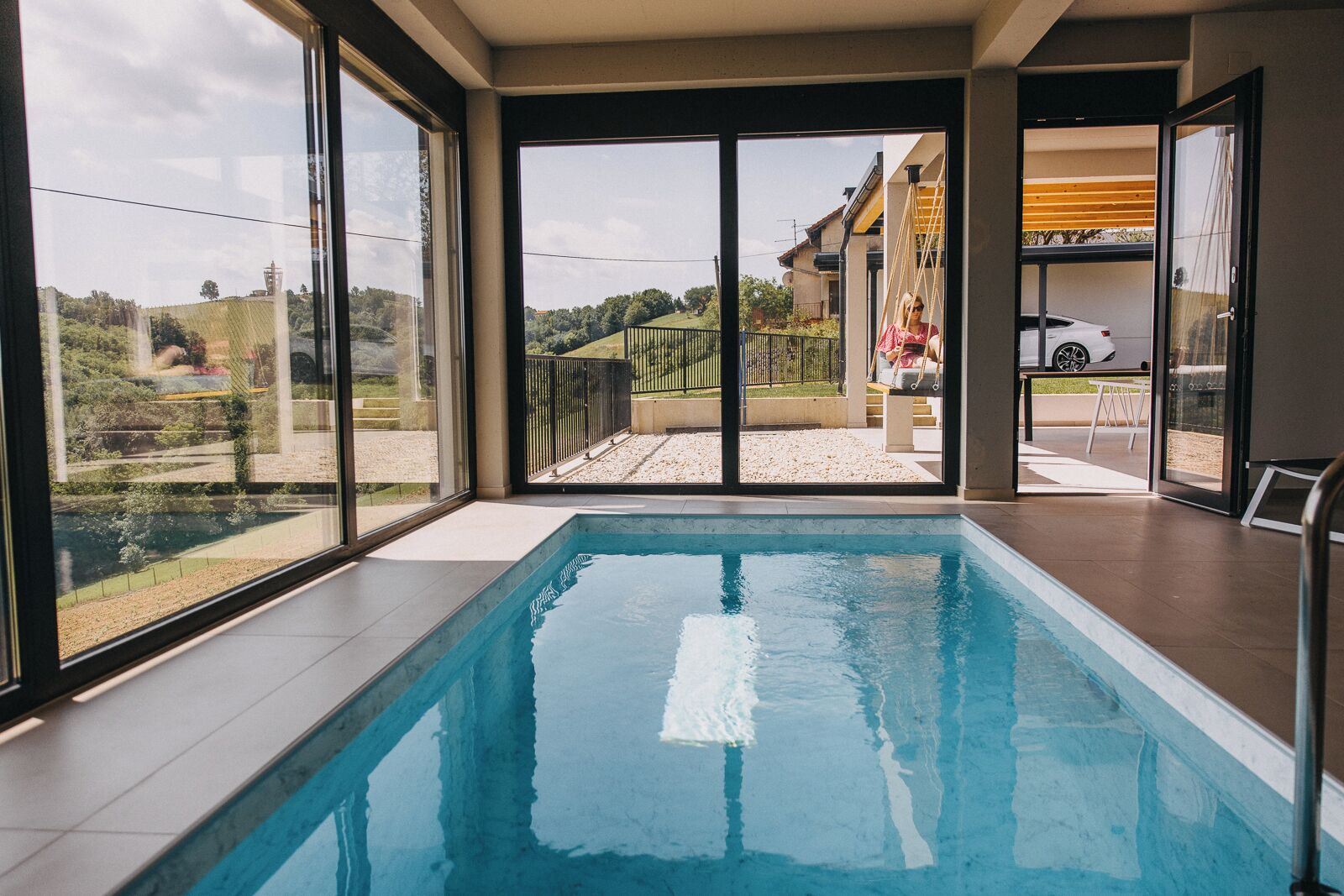 Piscina interior moderna con grandes ventanales que ofrecen vistas a una zona residencial.