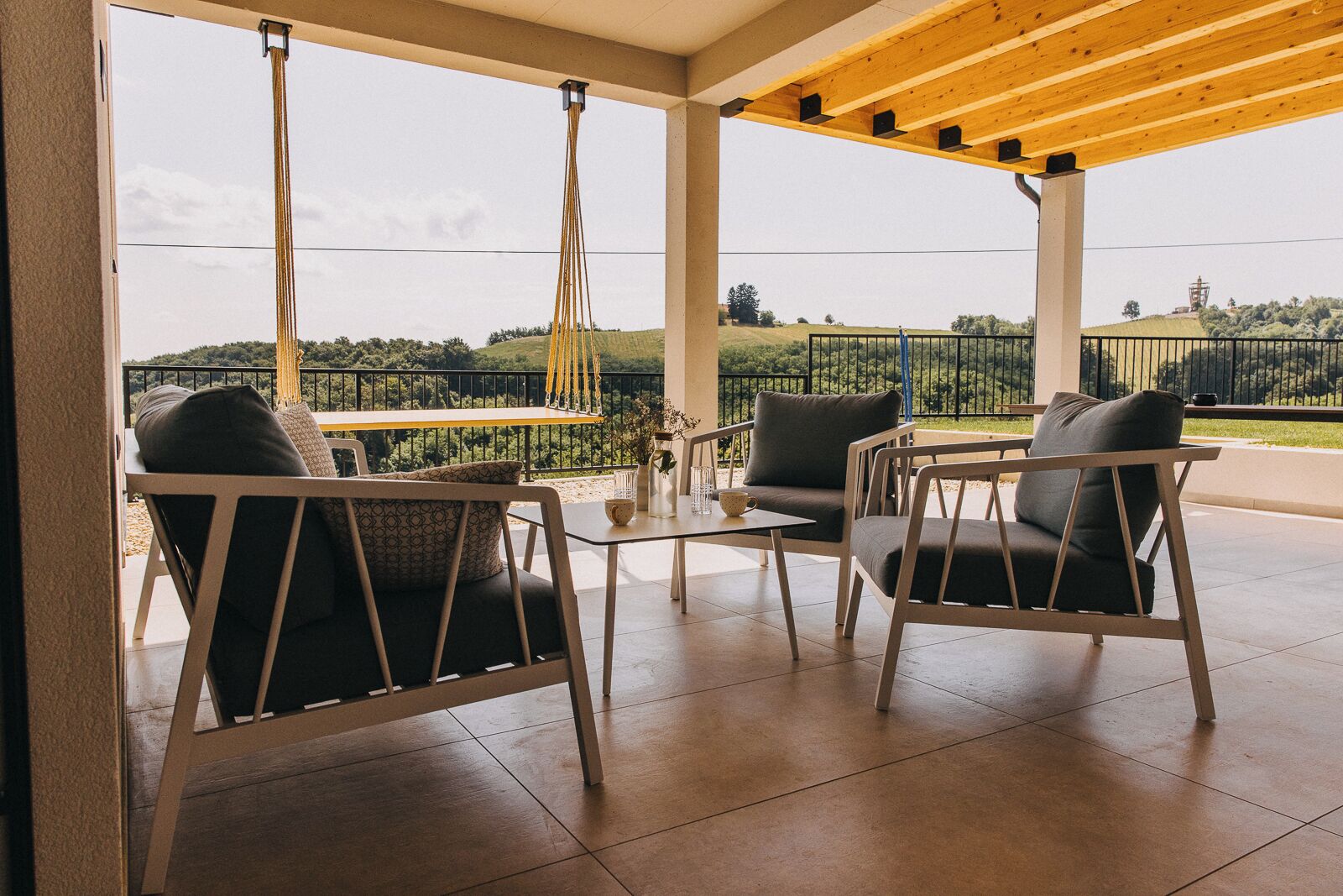 Un espace extérieur aménagé avec une zone de repos couverte, comprenant deux chaises et une table, et offrant une vue sur un paysage pittoresque.