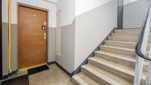Un escalier muni d’une rampe, une porte en bois portant le numéro 42, et un tuyau jaune qui longe le mur.
