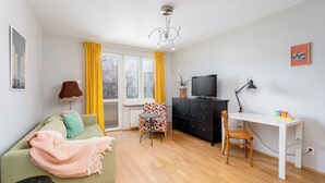 Un salon avec un canapé, un téléviseur, un bureau et une chaise.