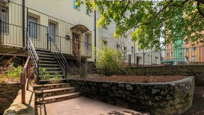Un escalier menant à un bâtiment doté d’un mur de soutènement en pierre et d’un petit jardin.