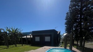 Una piscina con lettini, un edificio moderno e cielo sereno.