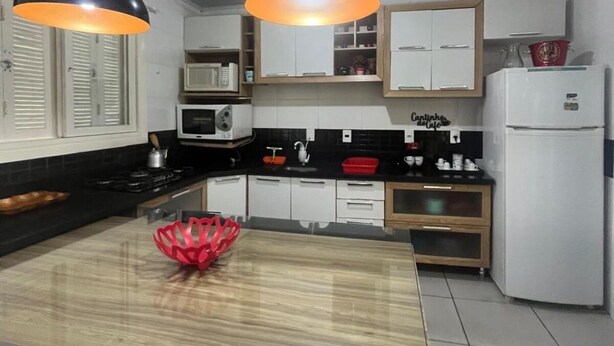 Una cucina moderna con isola centrale, mobili bianchi e luci a sospensione.