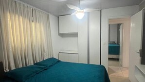 Una camera da letto con un letto, una ventola a soffitto, un armadio e una porta che conduce a un'altra stanza.