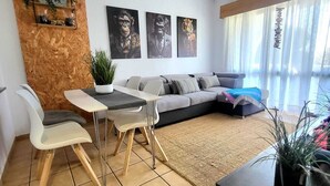 A modern living room with a sofa, dining table, chairs, and artwork on the wall. - CHABELLA! Charm Beach Lofts Apartments - Garden & Sea View - CARVOEIRO - ALGARVE (Carvoeiro)
