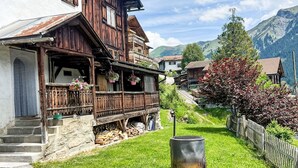Ein traditionelles Holzhaus mit Balkon, einem kleinen Grill und Blick auf die Berge.