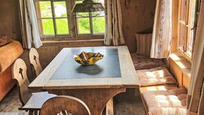 Ein gemütliches Zimmer mit Holztisch, Schale, Bank und einem Fenster mit Vorhängen.