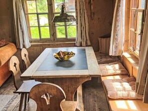 Una habitación acogedora con una mesa de madera, un cuenco, un banco y una ventana con cortinas.