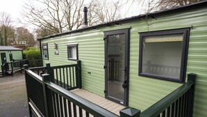 A green mobile home with a wooden deck and black railings. - The Lake House - Quiet, Dog Friendly, By the Lake, Free Parking (Bowness-on-Windermere)