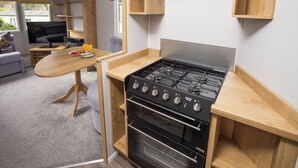 A compact kitchen with a stove, oven, and wooden shelves. - The Lake House - Quiet, Dog Friendly, By the Lake, Free Parking (Bowness-on-Windermere)