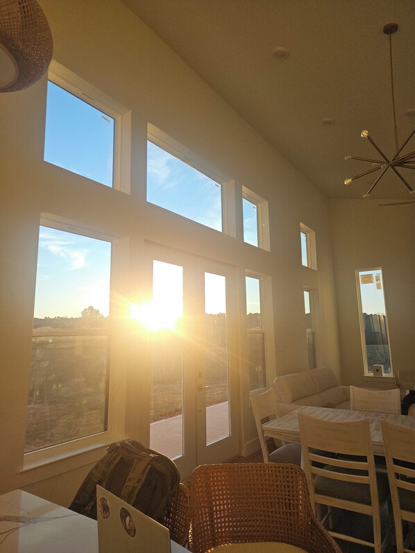 Una habitación con varias ventanas, una lámpara en el techo y una mesa con sillas.