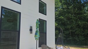 Een modern huis met terras, met rieten stoelen, een hangstoel en een kleine tafel met parasol.