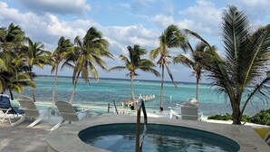 A pool area with lounge chairs, a hot tub, and a view of the ocean. - Cottage By The Sea ~Wonderful Family Friendly 2-bedroom with AC in East End (East End)