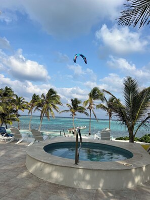 Un espace piscine avec des chaises longues, un jacuzzi et une vue sur l’océan.