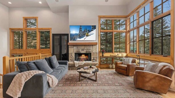 A spacious living room with a fireplace, large windows, and a cozy seating area. - Abode at Elkhorn Village, hot tub, steps to skiing (Sun Valley)