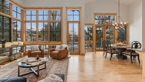 A spacious room with large windows, a dining area, and a cozy seating area. - Abode at Elkhorn Village, hot tub, steps to skiing (Sun Valley)
