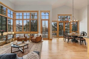 A spacious room with large windows, a dining area, and a cozy seating area.