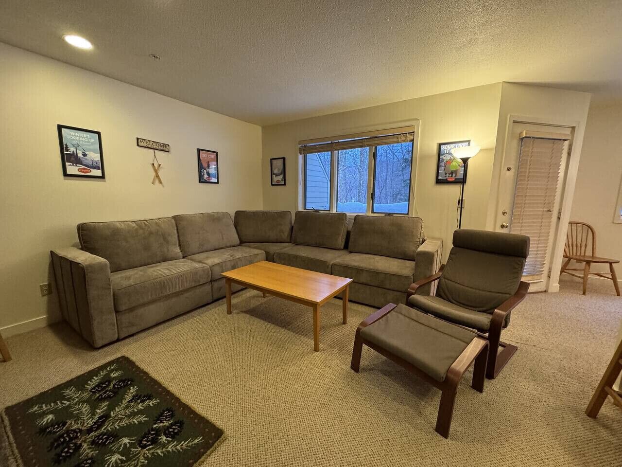 Een woonkamer met een hoekbank, een houten salontafel en een verstelbare fauteuil.
