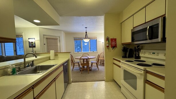 Una cucina con zona pranzo, forno a microonde, piano cottura e lavello.