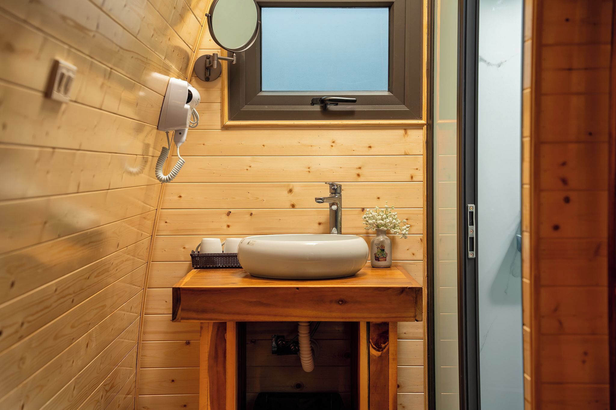 A wooden bathroom with a sink, mirror, and towel rack.