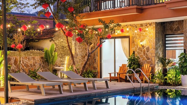 A poolside area with lounge chairs, a stone wall, and a door marked "102". - Tam Coc Pamela Homestay (Nam Hoa Lu)