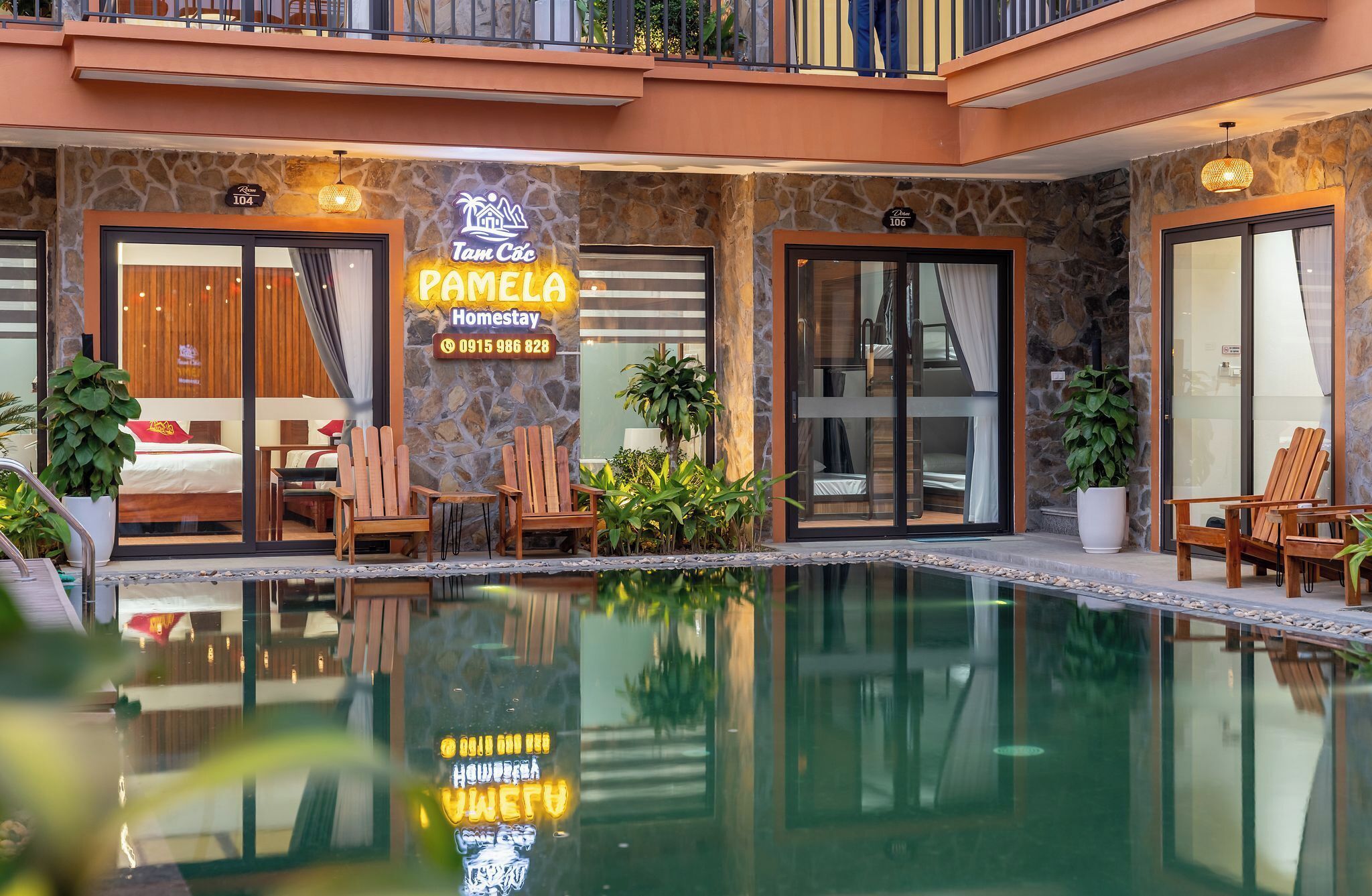 Un hôtel appelé Tam Cac, doté d’une piscine, de chaises en bois et d’un lit visible à travers les portes vitrées.