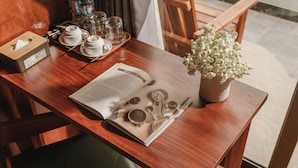 A wooden table with a book, teacups, a teapot, and a vase of white flowers. - Tam Coc Pamela Homestay (Nam Hoa Lu)