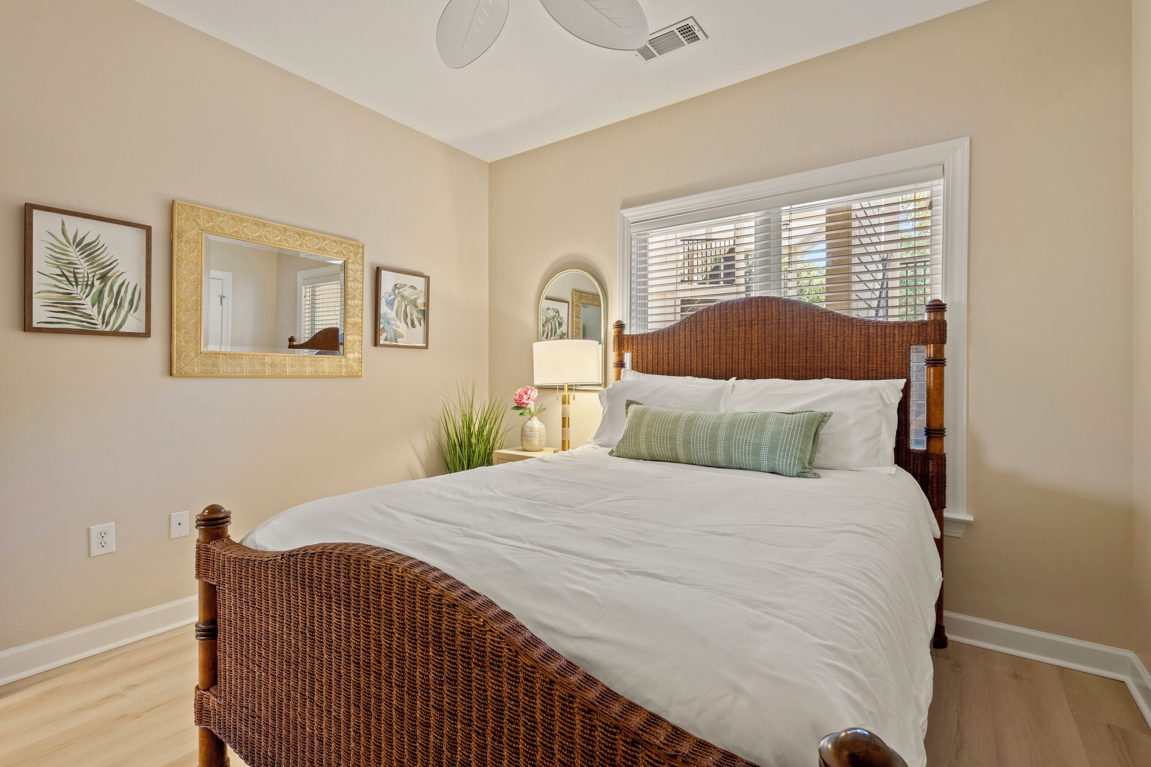 A bedroom with a large bed, a mirror, and a window with blinds.