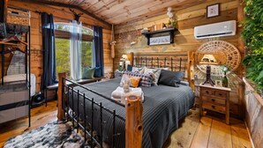 A cozy wooden cabin bedroom with a bed, bedside table, and a window with curtains. - Bigfoot's Hideout - Treehouse, Arcade, Hot Tub (Blue Ridge)