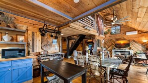 A cozy wooden interior with a dining area, kitchen, and a fireplace. - Bigfoot's Hideout - Treehouse, Arcade, Hot Tub (Blue Ridge)
