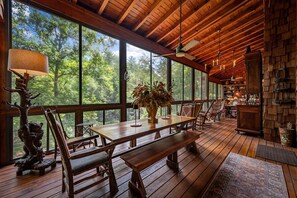 Un intérieur en bois comprenant une table à manger, des chaises, un vase avec des fleurs et une cheminée.
