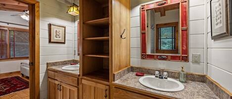 Un bagno con mobili in legno, due lavandini, uno specchio con cornice decorativa e una finestra con persiane.