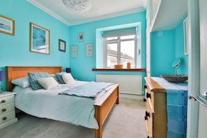 A bedroom with a bed, a dresser, and a window with a view of buildings.