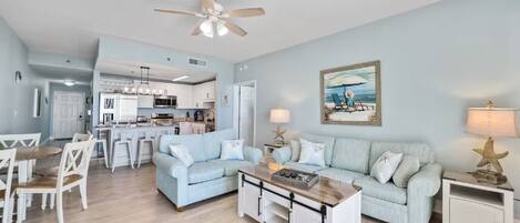 A spacious living room with a light blue sofa, a coffee table, and a dining area with white chairs.