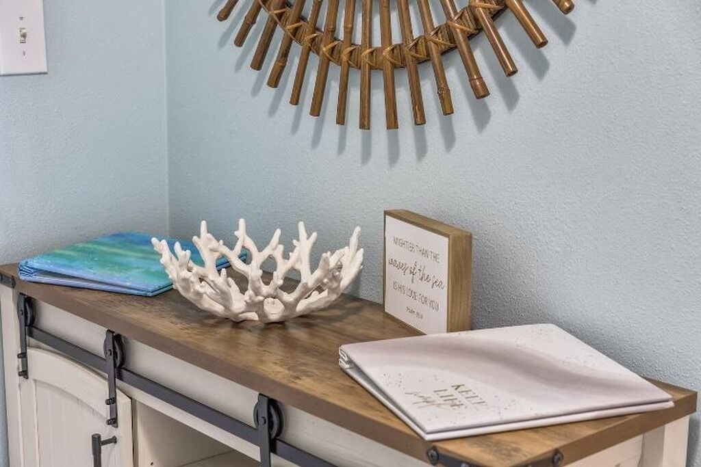 Un bureau en bois orné d’un élément décoratif en corail, d’une citation inspirante encadrée et d’une feuille de papier blanche pliée.