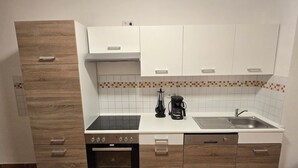 A compact kitchen with a built-in oven, a coffee maker, and a sink. - Spacious 75 sqm apartment with balcony and parking space (Chemnitz)