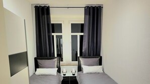 A room with two beds, a small table, and a chair. - Spacious 75 sqm apartment with balcony and parking space (Chemnitz)