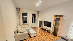 A modern living room with a sofa, a coffee table, a TV, and a wooden cabinet. - Spacious 75 sqm apartment with balcony and parking space (Chemnitz)