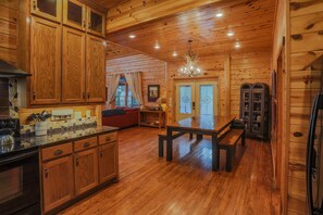 A wooden cabin interior with a kitchen, dining area, and living room. - Cozy 3-bedroom cabin in gorgeous Broken Bow with view and privacy (Broken Bow)