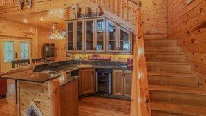 Ein Holzblockhaus-Innenraum mit Küche, Essbereich und einer Treppe.