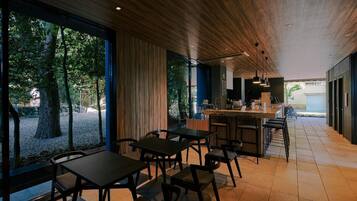Un'area pranzo moderna con soffitto in legno e ampie finestre affacciata su un giardino.