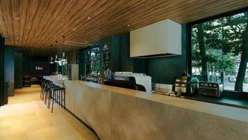 Angolo bar moderno con soffitto in legno, sgabelli da bar e un bancone con macchina del caffè e tostapane.
