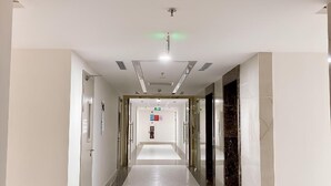 A hotel corridor with a white carpet, marble flooring, and glass doors on both sides. - Can H Du L Ch View Bi N Pullman Building (Quy Nhon)