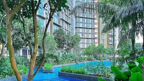 A pool surrounded by lush greenery and modern buildings in the background. - The Elysia Suites (Iskandar Puteri)