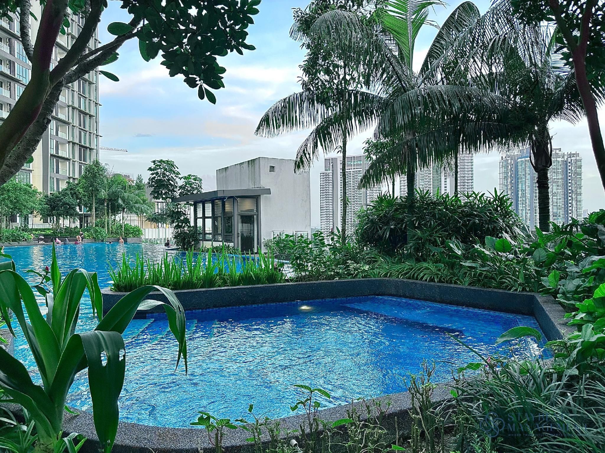 A swimming pool surrounded by lush greenery and tall buildings in the background.