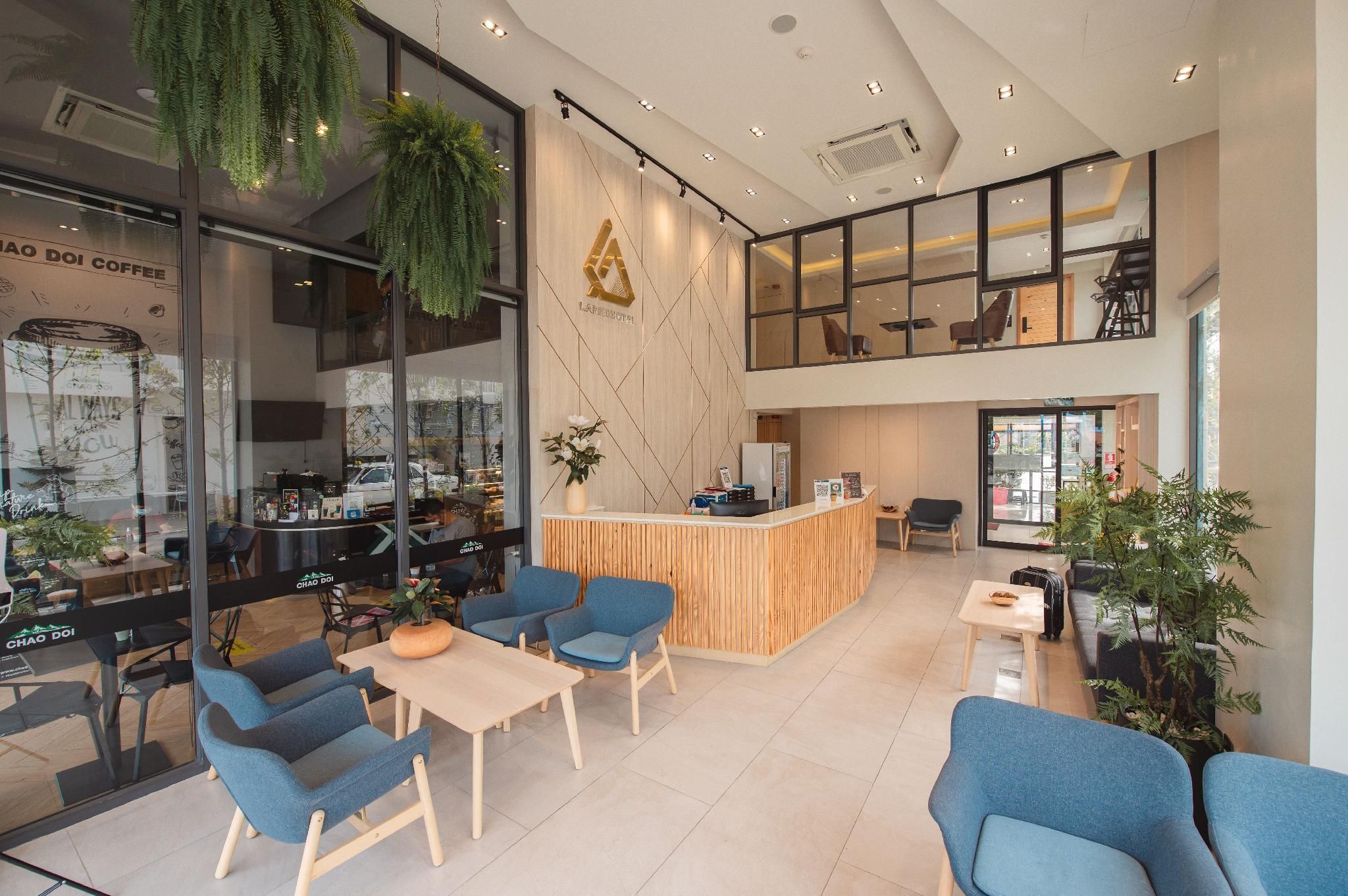 Interior moderno de una cafetería con mostrador de madera, sillas azules y plantas colgantes.