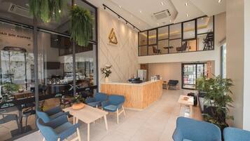A modern coffee shop interior with a wooden counter, blue chairs, and hanging plants.