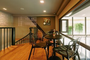 A modern cafe interior with wooden flooring, black metal chairs, and a wall with coffee-related words. - La Pino Hotel (Songkhla)