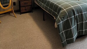 Un dormitorio con cama, cómoda, espejo, ventilador de techo y ventana.