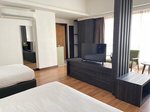 A hotel room with a bed, a TV on a stand, a desk, and a chair. - Win Hotel (Sibu)